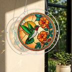 Round acrylic hummingbird puzzle suncatcher displayed by a bright window with orange flowers and warm golden artwork.