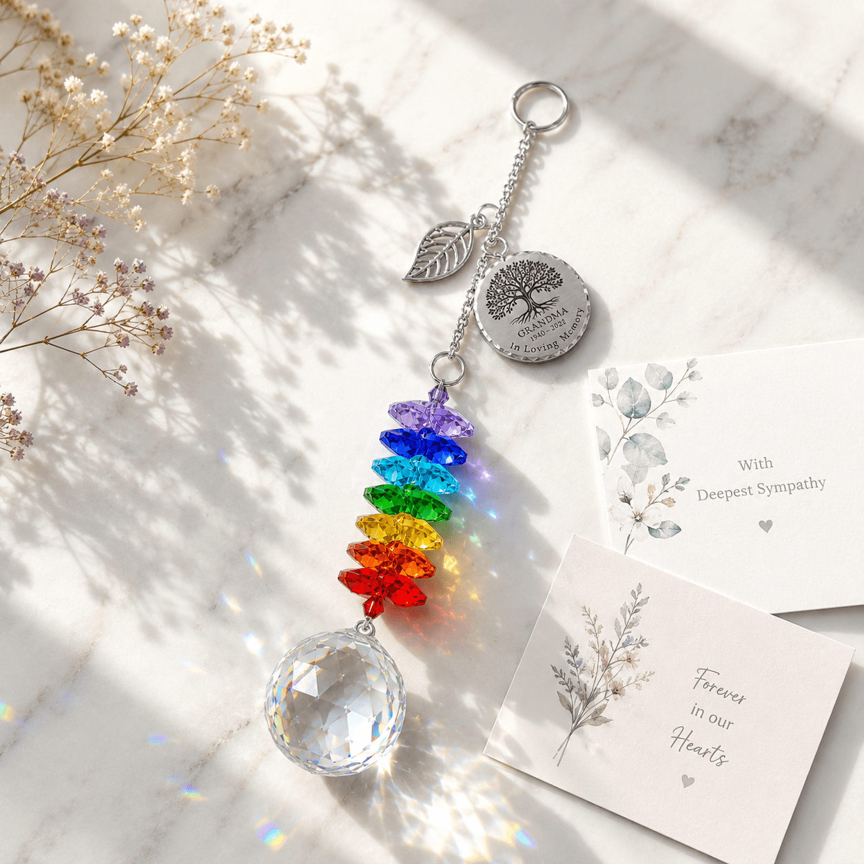 Personalized Tree of Life memorial crystal suncatcher displayed on marble surface with sympathy card, rainbow crystals, and soft sunlight