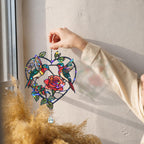 Hand holding a two hummingbirds rose heart holographic acrylic suncatcher near a sunny wall with soft shadows.
