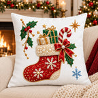 Embroidered Christmas pillow cover with a ruby stocking, candy cane and holly stitched on white canvas, fireplace behind